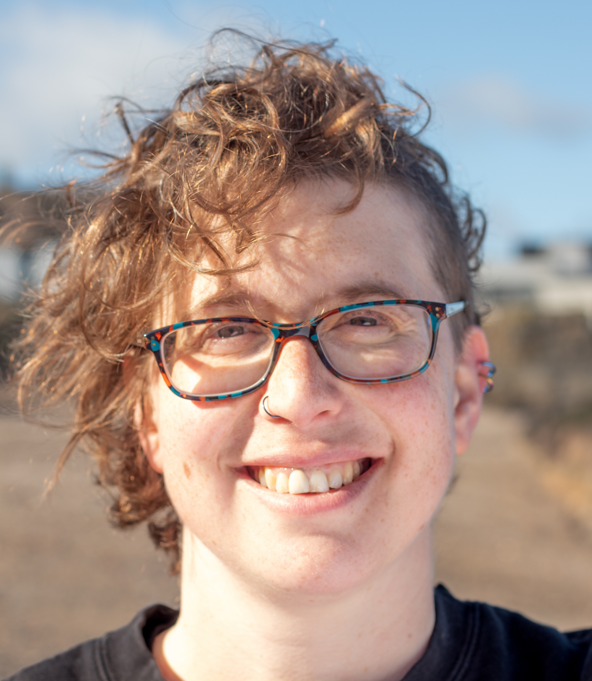 A photo of Rebs on the beach, smiling at the camera.